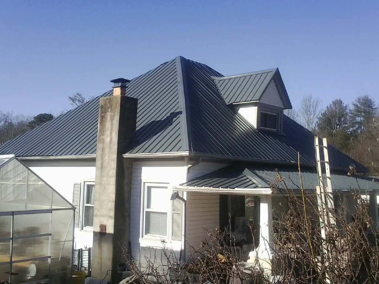 Dark blue standing seam metal roof on a white farmhouse with dormer — Slate & Tile Roof Repair by Roofing Brothers in Clarendon Hills