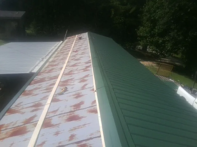 Old rusted panels beside newly installed green metal roofing — Wind Damage Roof Repair by Roofing Brothers in Clarendon Hills