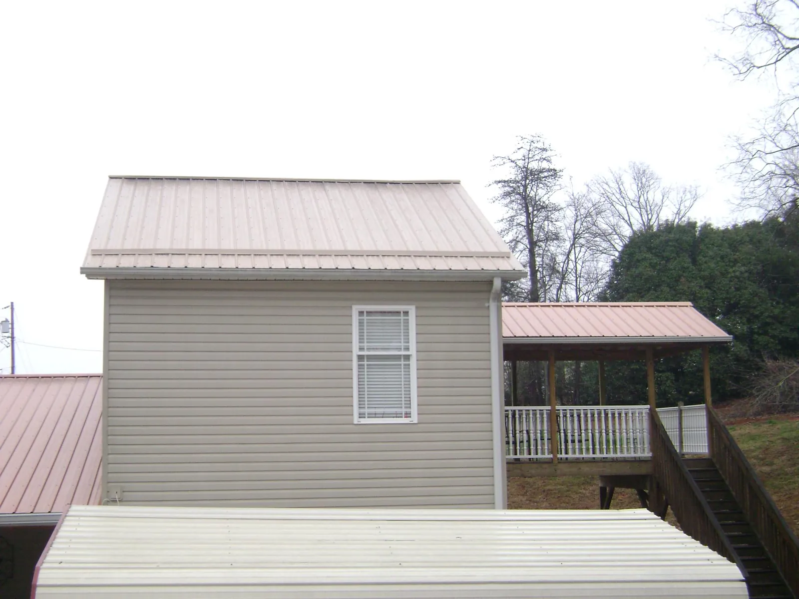 Tan metal roofs on a two story addition and attached porch, from a Roof Replacement job in Clarendon Hills