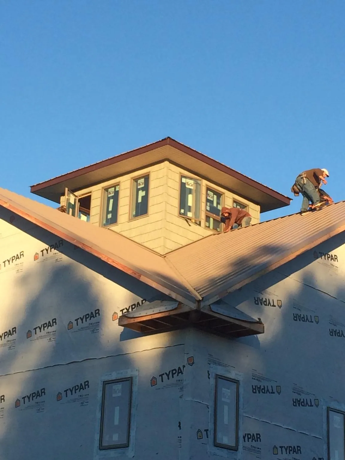 Roofers working around a rooftop cupola on a new metal roof at sunset — Roof Waterproofing in Clarendon Hills by Roofing Brothers